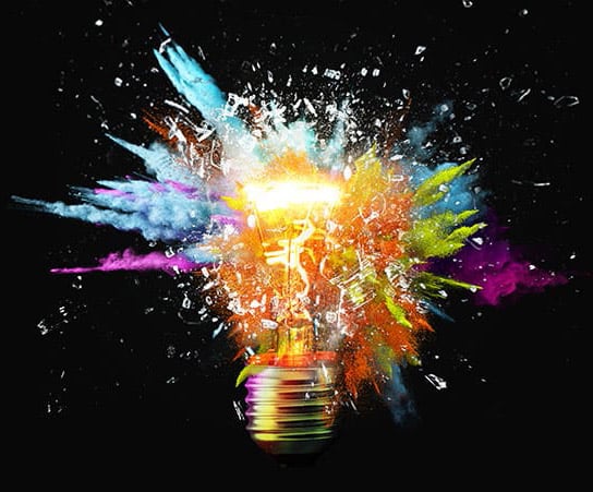 Creative light bulb explodes with colorful paint splashes and shards of glass on a black background. Think differently creative idea concept. Dry paint splatter. Brainstorm and think