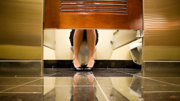 Female woman's feet showing out the bottom of a public bathroom stall.