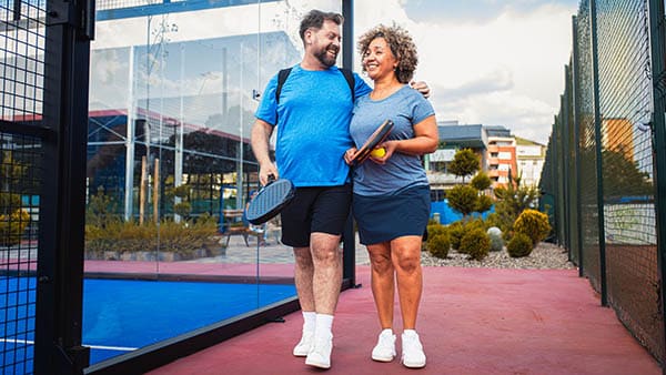 Smiling couple comes to the outdoor court to play pickle ball.