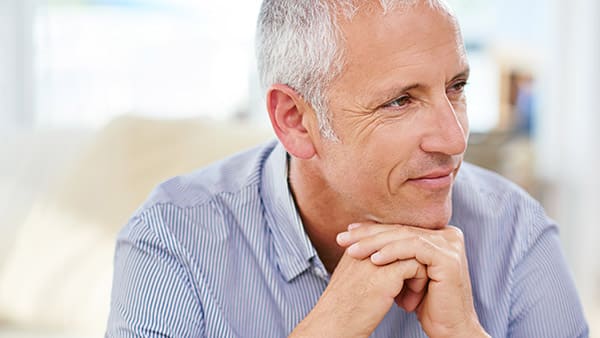 Shot of a mature man sitting on his sofa deep in thought